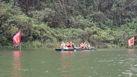 turistas remando en un barco en el río con banderas