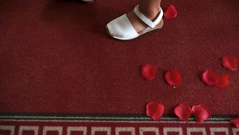 red petals falling on the ground being thrown by a girl at a wedding