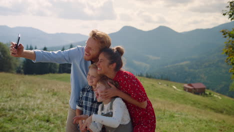familia divertida haciendo selfies en las montañas. padres tomando fotos con los niños