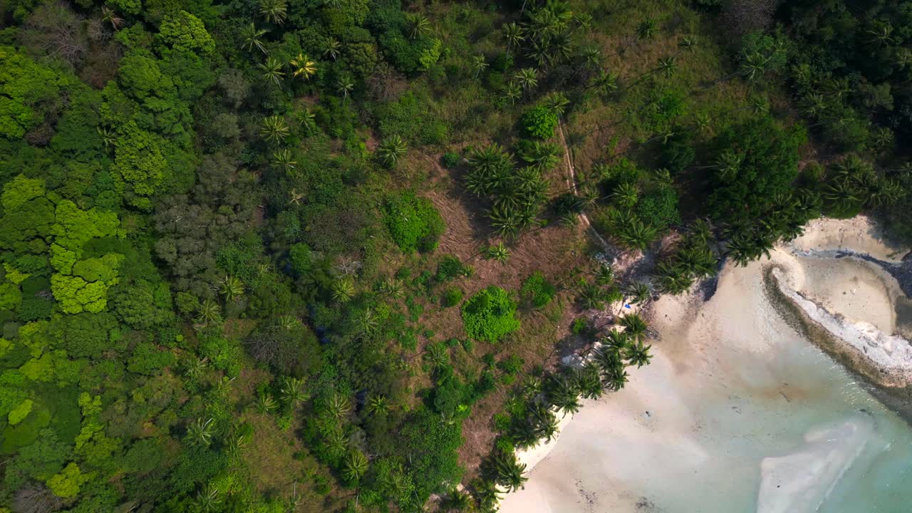 Crystal clear turquoise water gently washing pristine white sand beach next to tropical vegetation in idyllic paradise koh chang thailand. Fabulous aerial view flight drone shot footage from above