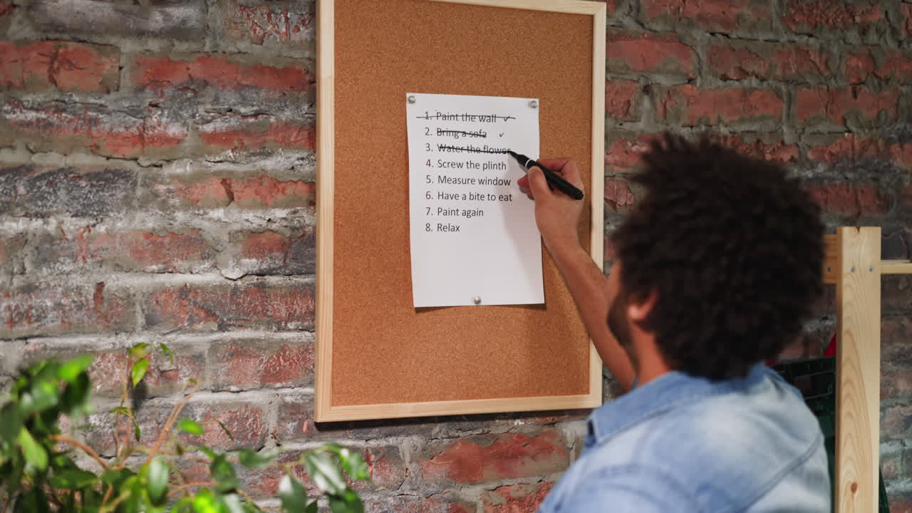 Man crosses out accomplished to-do list points in room