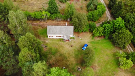 Una-Casa-De-Hormigón-Y-Un-Coche-Azul-En-El-Exuberante-Paisaje-Del-Pueblo-De-Lesno-En-El-Condado-De-Chojnice,-Polonia---Drone-Aéreo