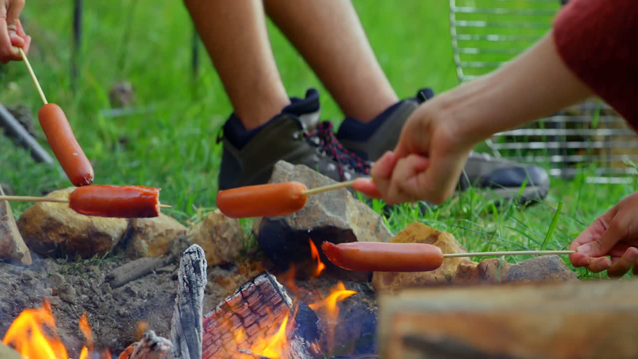 Man roasting hot dog on campfire 4k