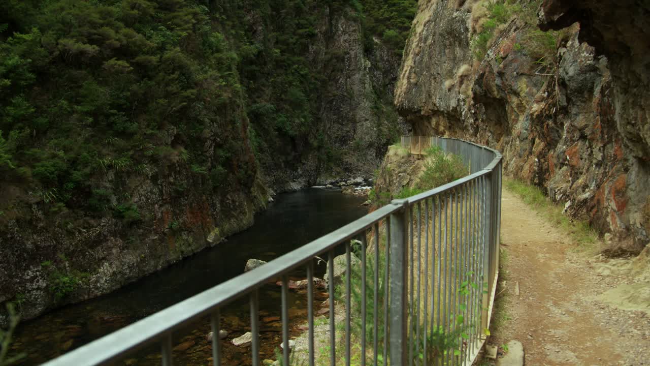 Walking track with steel railing along river in gorge canyon, no people, New Zealand