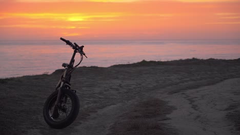 Spectacular-orange-sunset-and-an-electric-bicycle-in-the-foreground,-Half-Moon-Bay-California