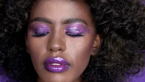 retrato en primer plano de una mujer con maquillaje púrpura y afro