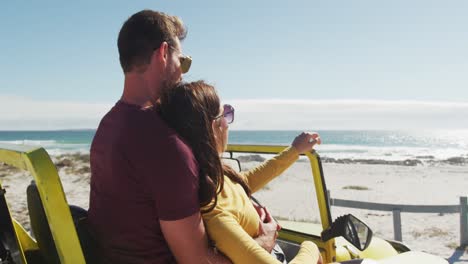 Happy-caucasian-couple-sitting-in-beach-buggy-by-the-sea-talking