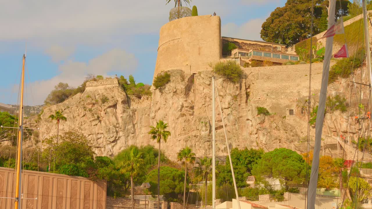 Vista all'ora d'oro della Rocca di Monaco con edifici storici sopra spettacolari scogliere calcaree che si affacciano sul Mar Mediterraneo.