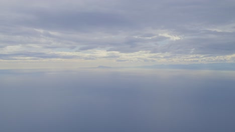 calm seascape under cloudy sky with distant mountains on the horizon