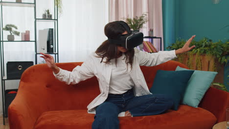 Una-Mujer-Joven-Usa-Gafas-De-Realidad-Virtual-En-Casa,-Disfrutando-Del-Concepto-De-Vídeo-Moviendo-Las-Manos-En-El-Aire