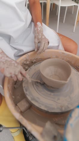 person's hands shaping clay on a pottery wheel