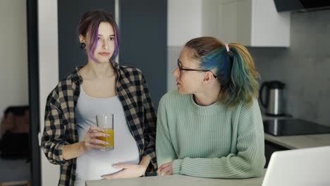 Pregnant-young-woman-enjoying-coffee-time-at-home-with-her-friend-or-mom