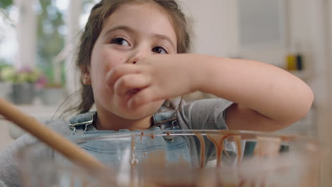 beautiful little girl baking in kitchen mixing chocolate sauce tasting ingredients for homemade cupcakes having fun preparing delicious treats