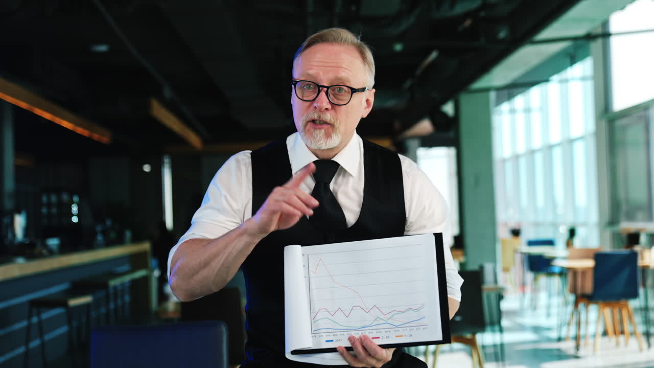 Successful senior businessman holding papers. Man displays the graphs and comments them.