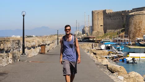 male tourist walking towards camera smiling along marina path near girne castile in nicosia