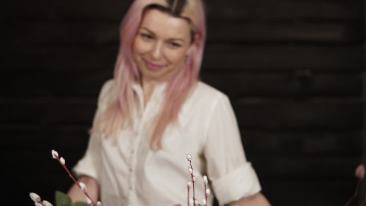 primer plano de un ramo colorido en la mesa cambiando a una imagen de una joven atractiva sonriendo. fondo oscuro. cámara lenta