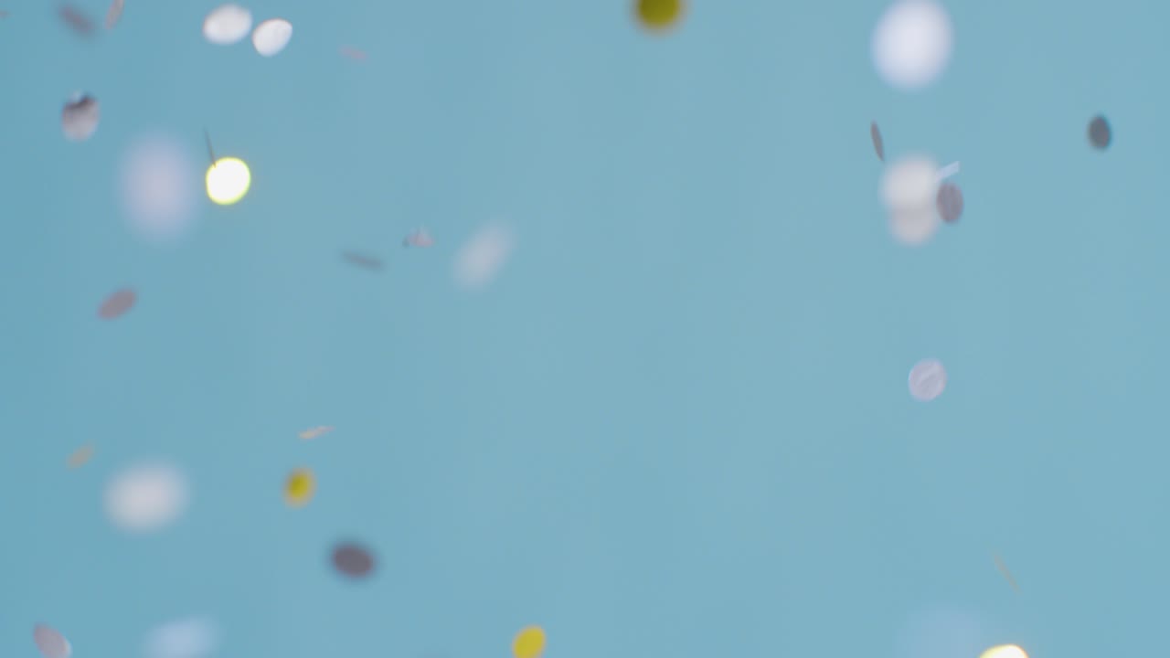 파란색 배경에 떨어지는 회색 및 금색 색종이의 고정 샷