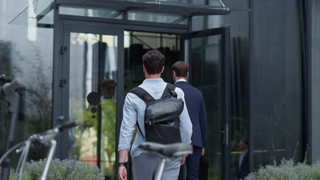 manager entering office building rear view. closeup bicycle electric scooter.