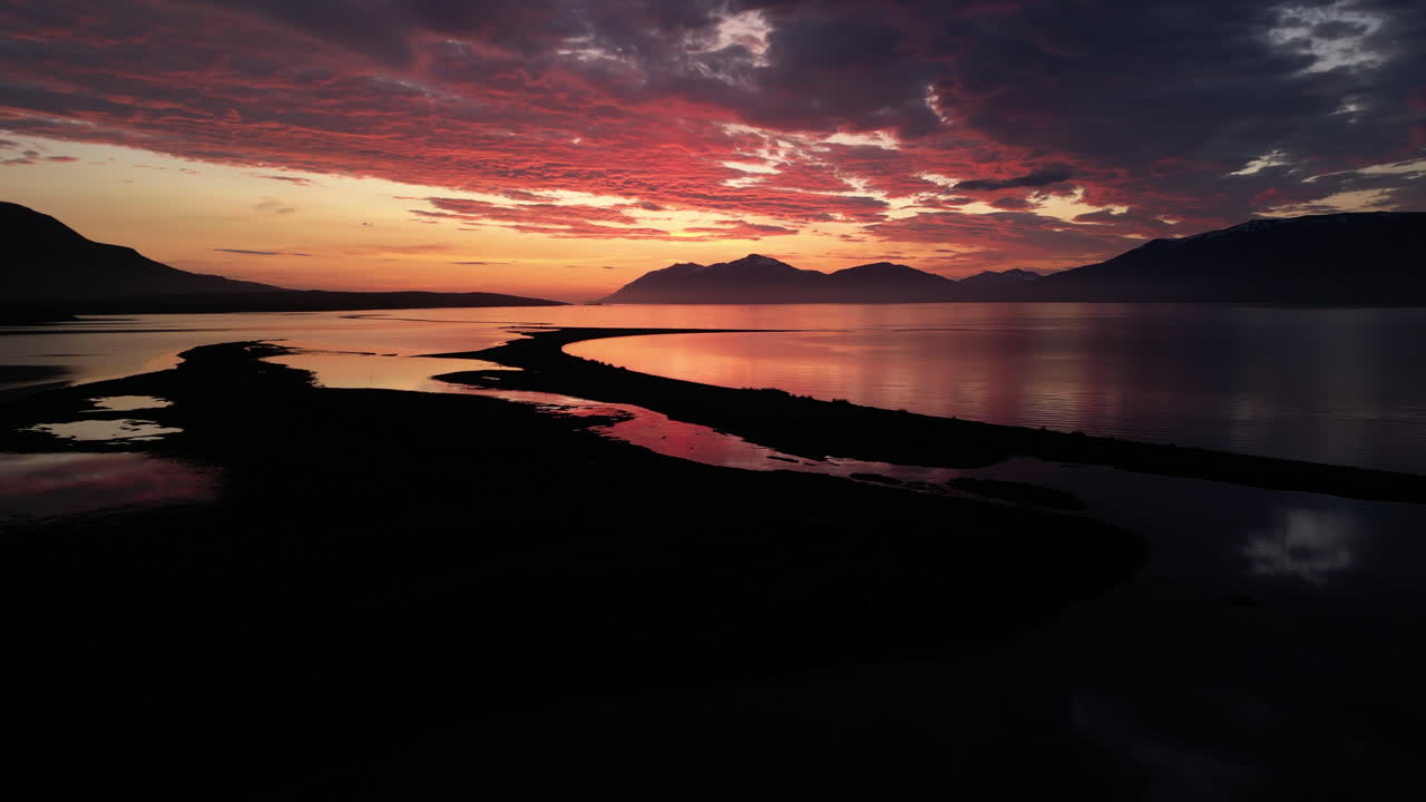 Smooth tilted up drone fly in Eyjafjordur fjord's serene sunset on coastal wetland, Northern Iceland