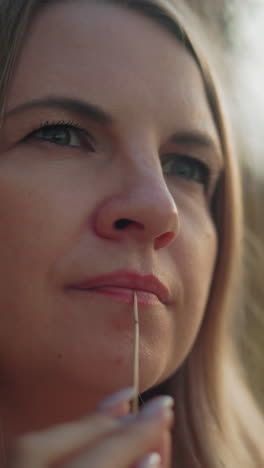 primer plano de una mujer de negocios perdida en sus pensamientos, sosteniendo suavemente un palo seco cerca de sus labios, sus ojos reflejan una profunda contemplación, en un fondo de campo suavemente borroso