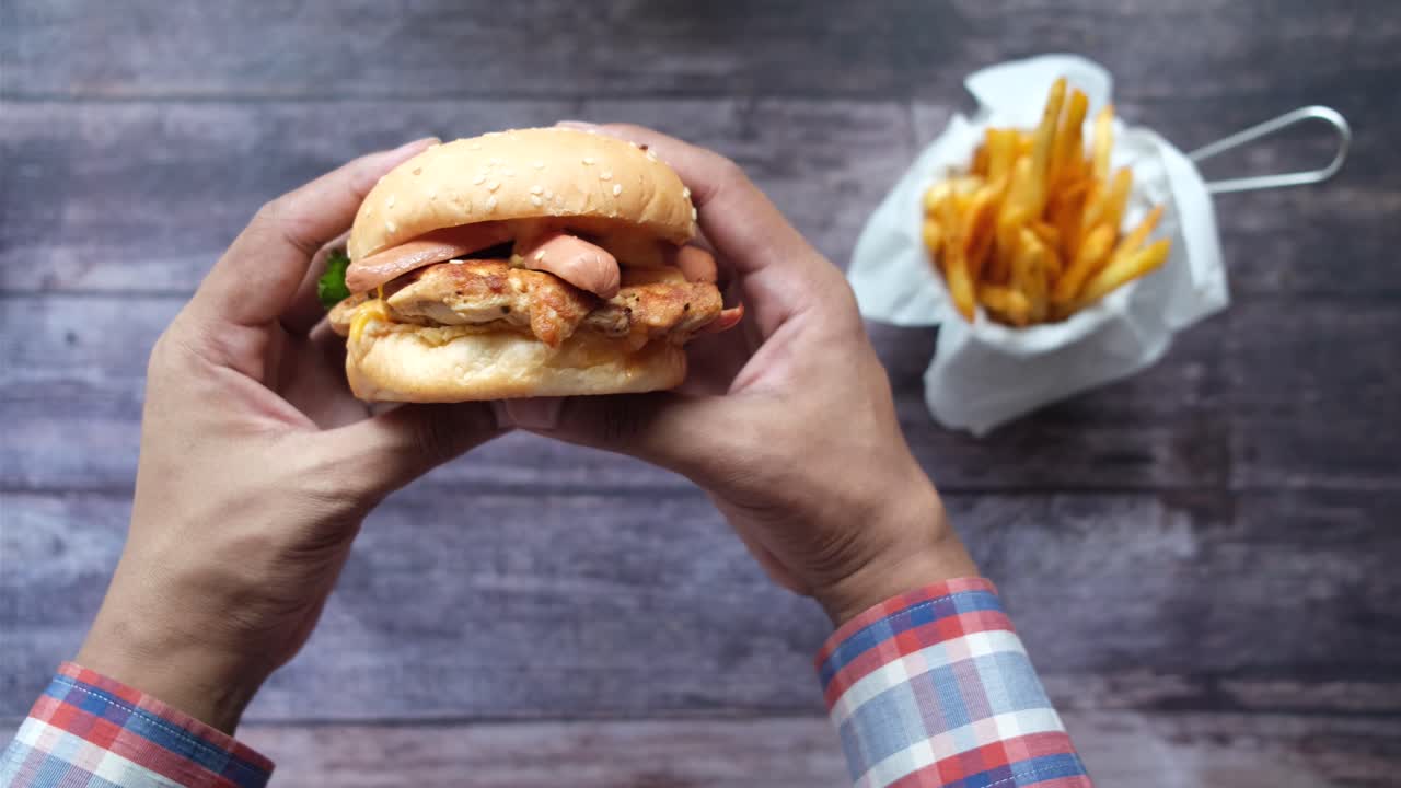 mano sosteniendo una hamburguesa con papas fritas