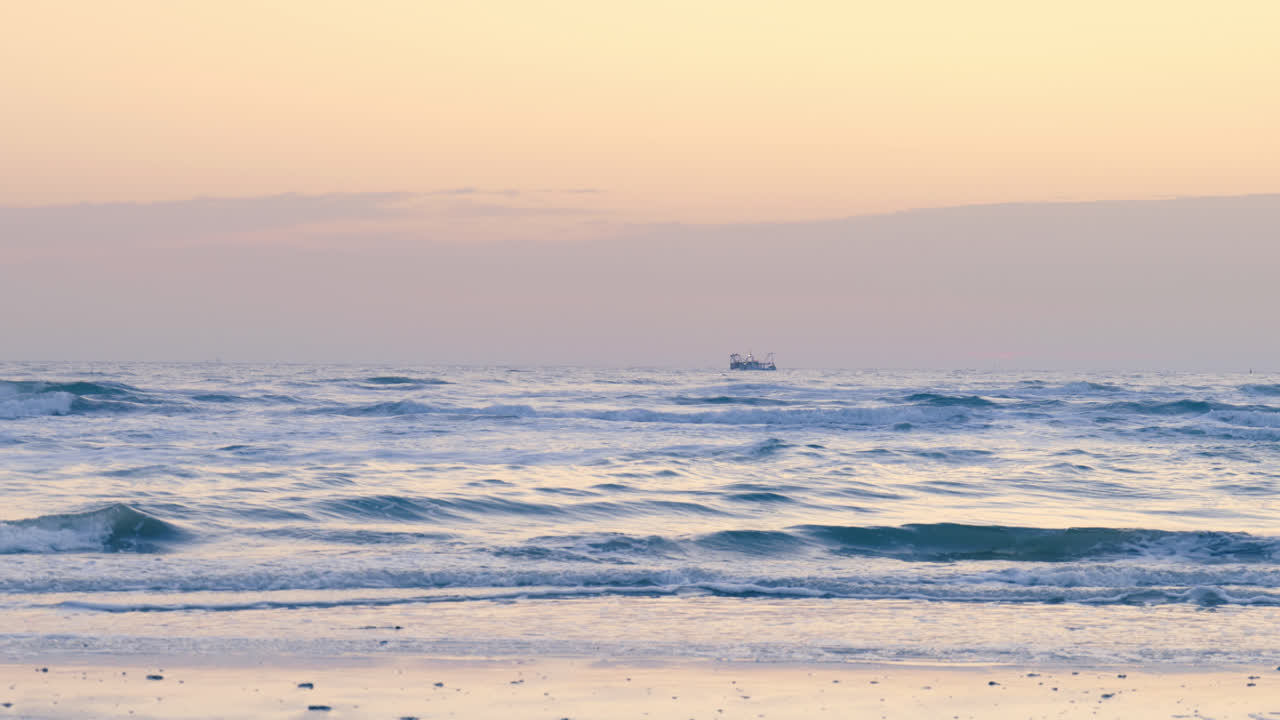 파스텔 색의 해가 지는 동안 조용한 바다에서 멀리 있는 시 배