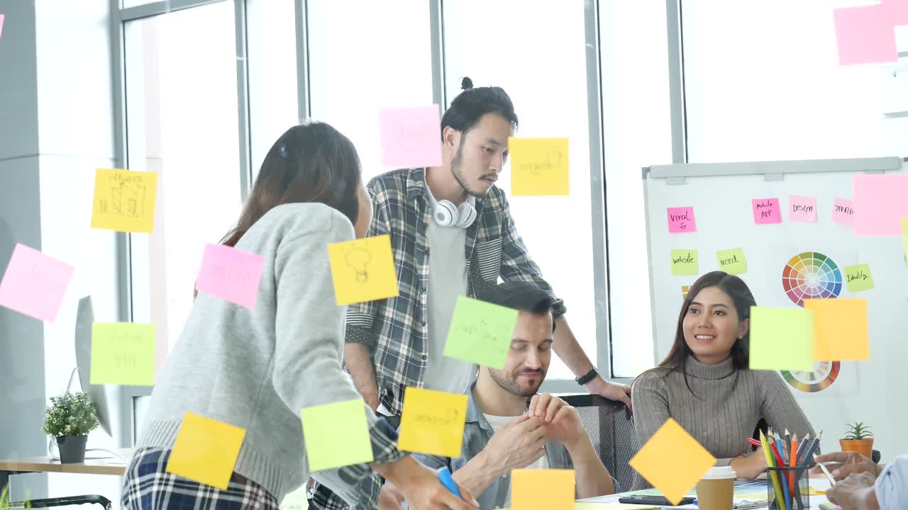 Diversity multi ethnic group brainstorming teams with business partner meeting and share ideas in conference room. Creative design colleague talking strategy plan use sticky notes post, present ideas