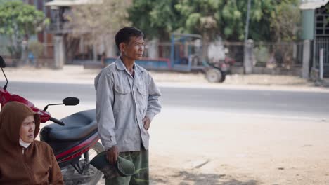 man standing on street, possibly a worker, near motorcycles