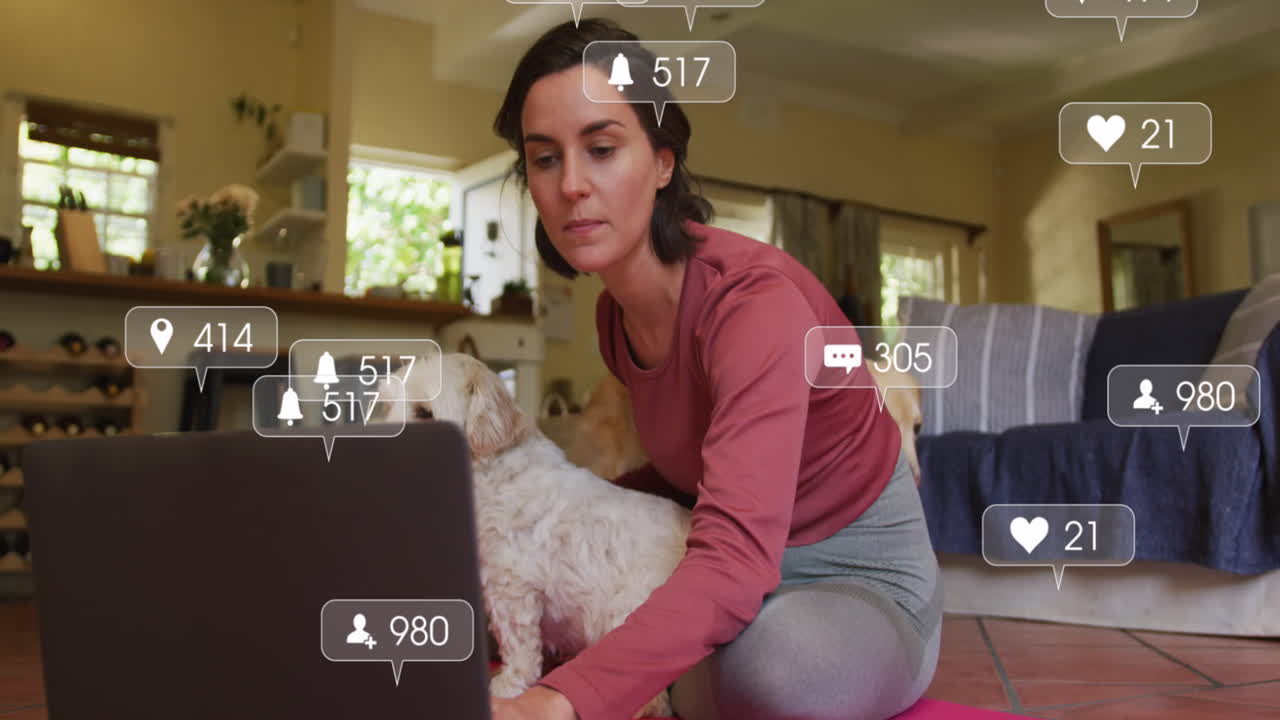 iconos digitales en burbujas de habla contra una mujer caucásica sentada con su perro usando una computadora portátil en casa