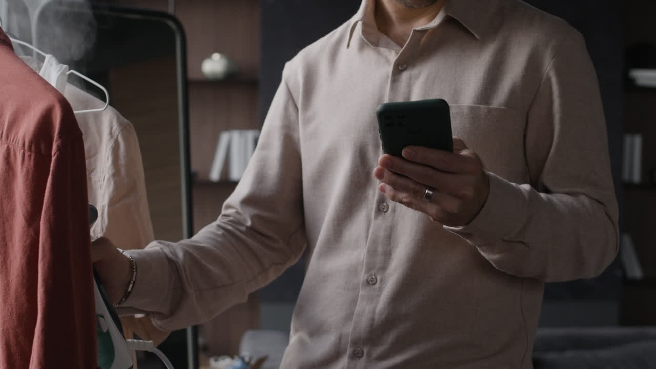 Man using phone and ironing clothes