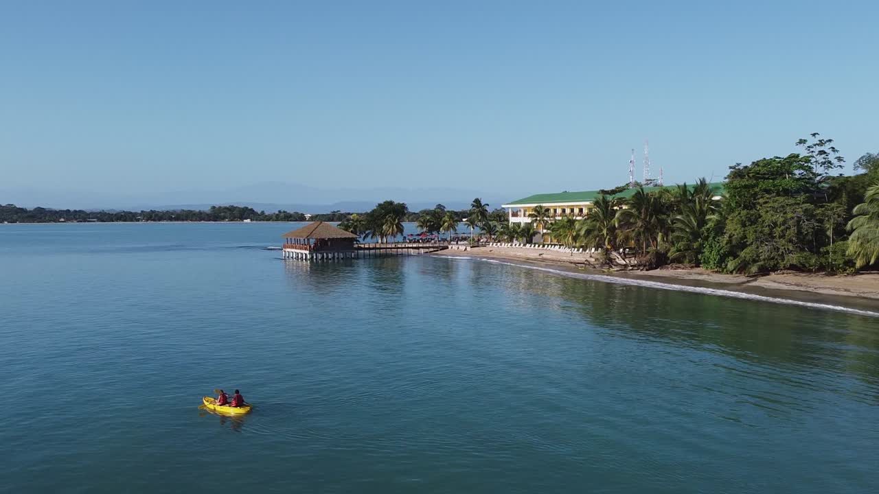 antena de panamá: kayakistas reman en playa tortuga con hotel resort dock