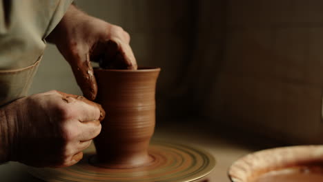 Unknown-clay-artist-sculpting-in-studio.-Man-hands-forming-jar-in-pottery