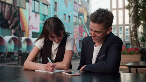 teenage boy and girl writing outdoors