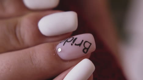 mujer sostiene hermosa mano manicurada con la palabra novia en la uña