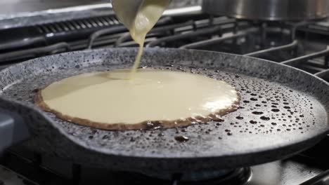 cuchara de cucharón vierte la masa de panqueques en aceite caliente en la sartén, desayuno de panqueques, cierre