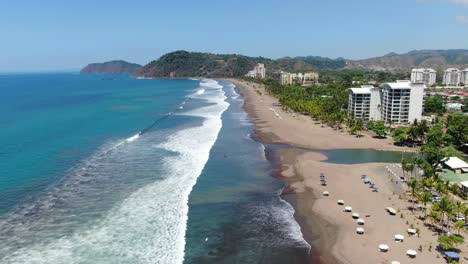 Costa-Rica-beach-drone-view-showing-sea,-shore-and-forest-on-a-sunny-day-over-the-pacific-ocean-in-Jaco