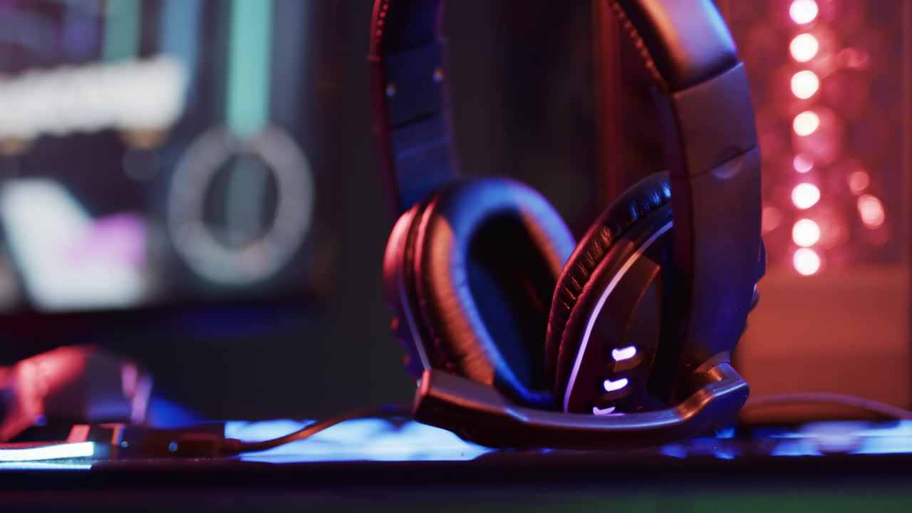 video de auriculares, computadoras y equipos de juegos en el escritorio con espacio de copia en fondo de neón