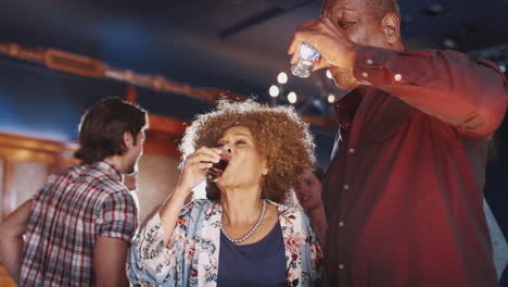 una pareja de mayores bebiendo copas y bailando juntos en el bar.