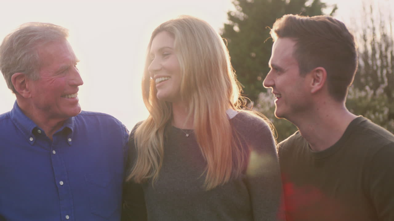 Portret van familie met volwassen ouders en volwassen zoon en dochter buiten tegen de felle zon