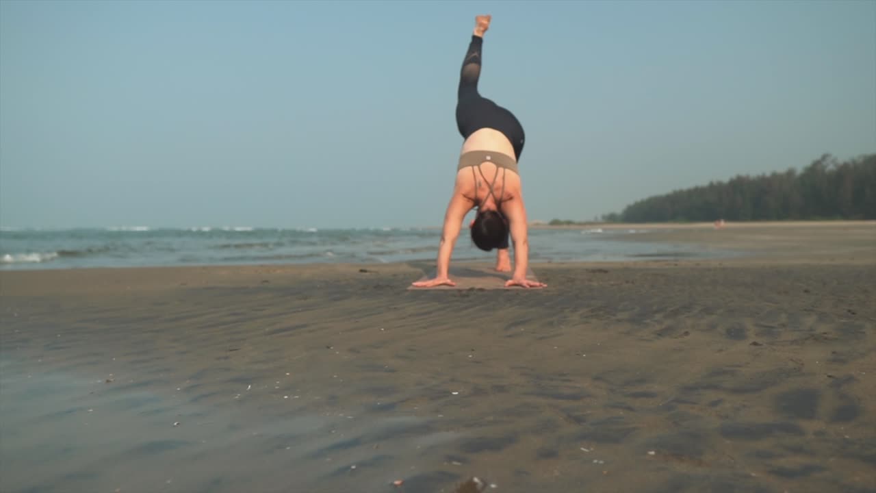 mujeres haciendo posición de yoga de tres patas en la playa mientras están de vacaciones
