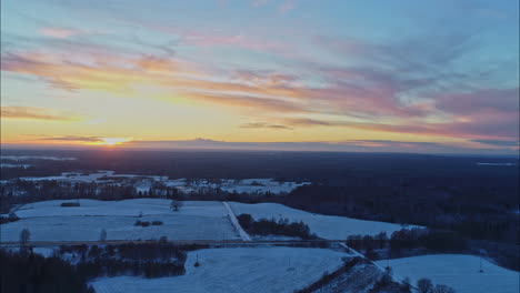 rising panoramic aerial view of a winter landscape with an orange sunset