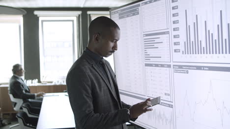 concentrated mixed-raced businessman using tablet, standing