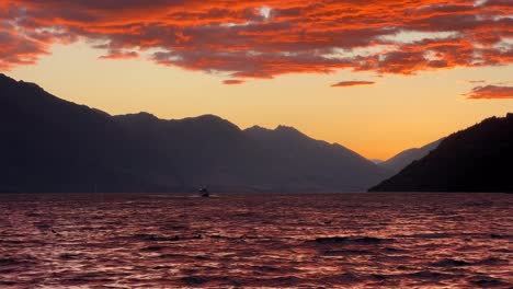 boat cruises on lake wakatipu in queenstown during golden sunset, orange clouds