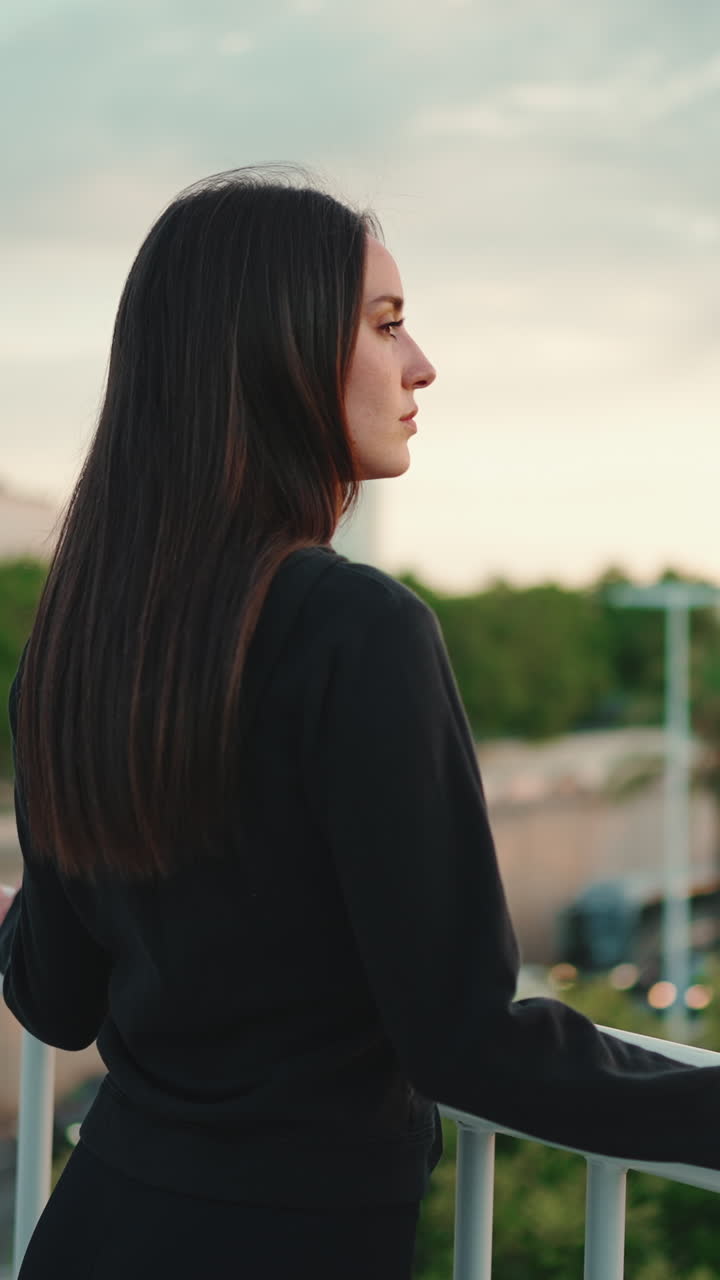 Woman with long brown hair looking at city skyline