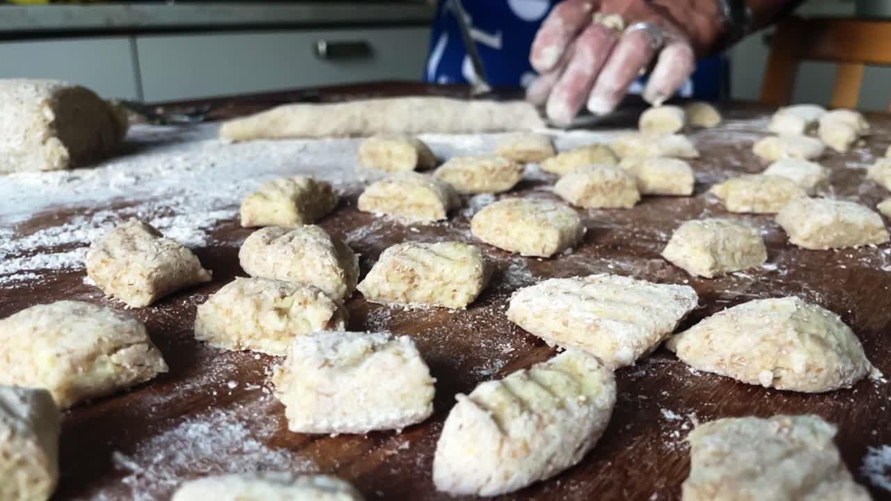 las manos del chef cortan gnocchi plato tradicional de pasta forma italia, dentro de la cocina primer plano en cámara lenta, preparación de alimentos