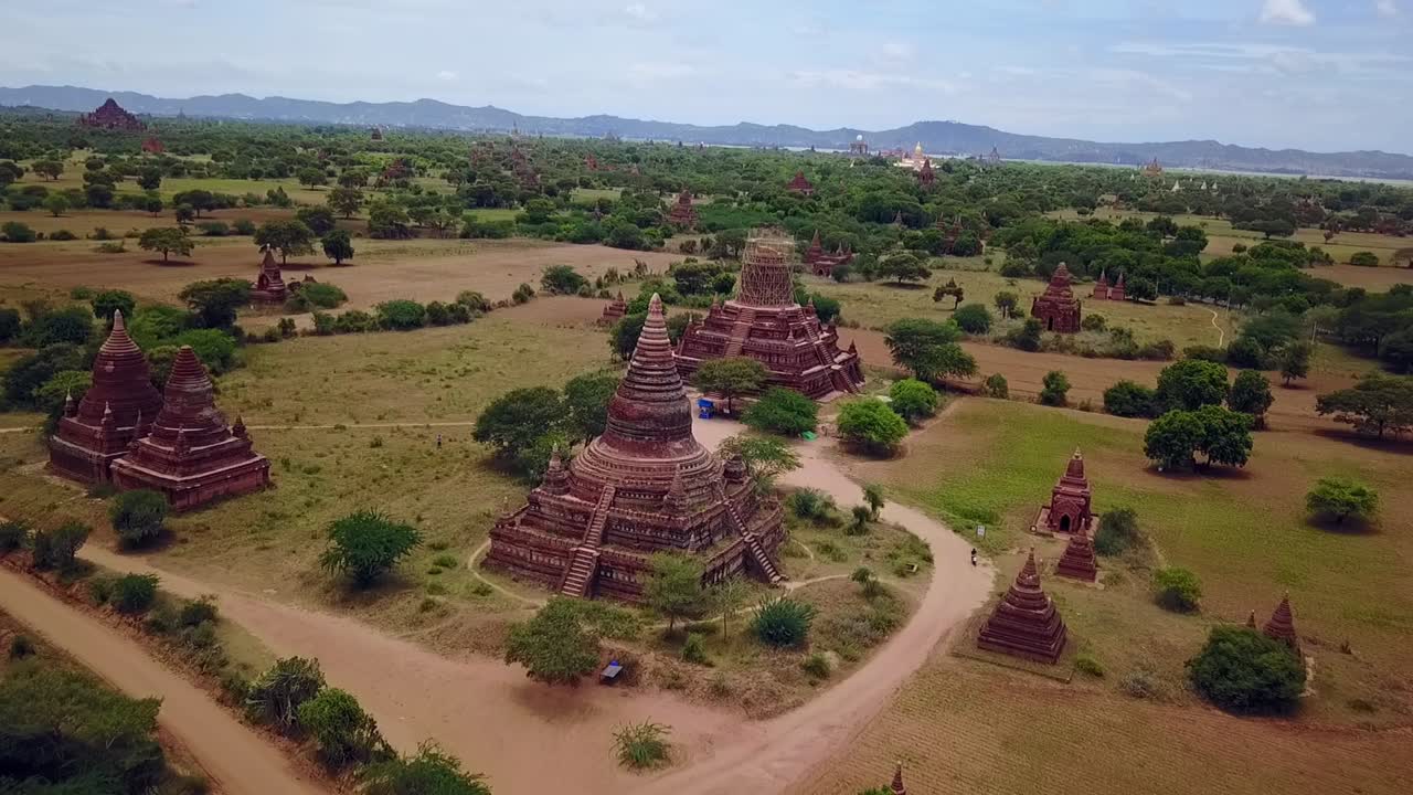 A forward dolly aerial shot creates a stunning panoramic view of Bagan’s temples, highlighting their red brick beauty set against a lush, green expanse. A blend of history and serenity