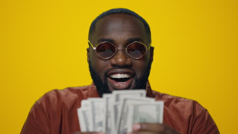 portrait of happy african american man counting money on yellow background.