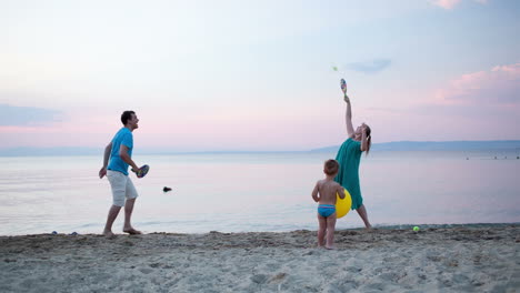 young family playing tennis at the seaside