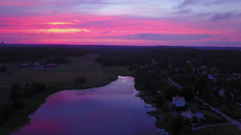 aerial descending, drone view backwards, above the countryside, purple sky, at a colorful sunset or dusk, at albysjon, tyreso, sweden