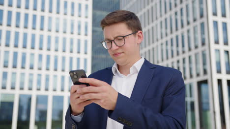 vista cercana de un joven hombre de negocios con gafas haciendo una llamada telefónica al aire libre